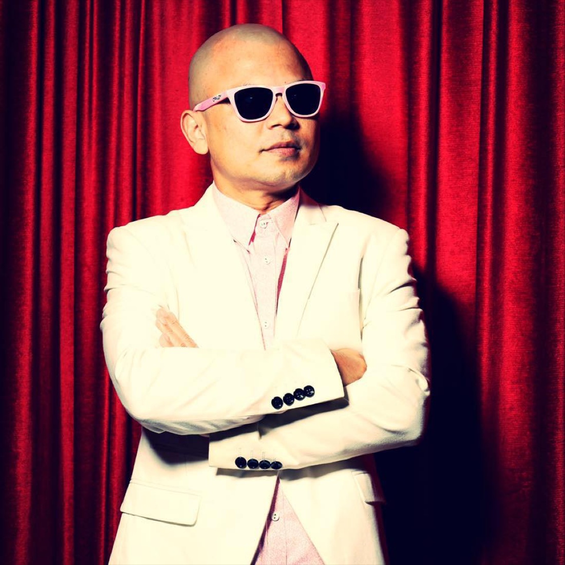 Formal portrait of DJ Kzee in front of red curtains